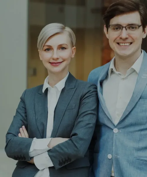 A man and woman in business attire smiling.